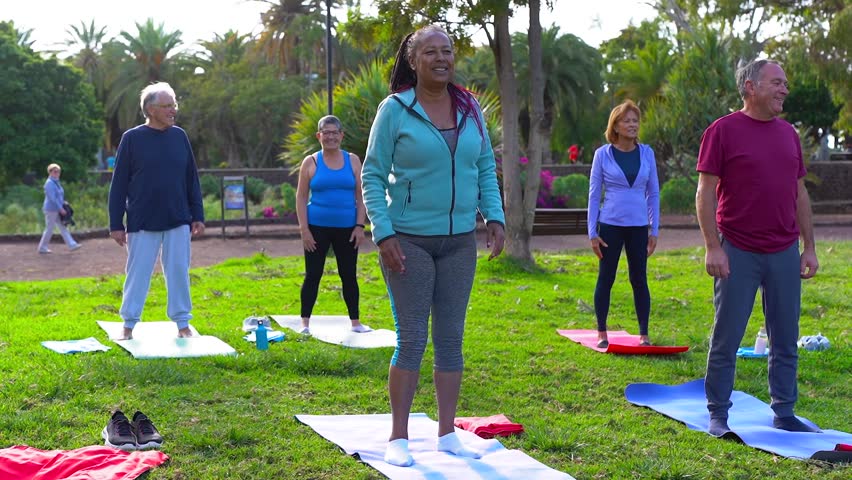 Fit senior people doing yoga exercise together at city park - Multiracial elderly community doing activity together outdoor - Healthy lifestyle concept - Powered by Shutterstock - Get 15% off with code: PIKWIZARD15