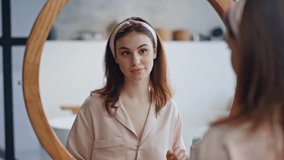 Attractive lady applying cream at morning skincare routine in bathroom mirror closeup. Calm woman enjoying selfcare looking at reflection with gentle smile. Portrait beautiful girl caring about skin. - Powered by Shutterstock - Get 15% off with code: PIKWIZARD15