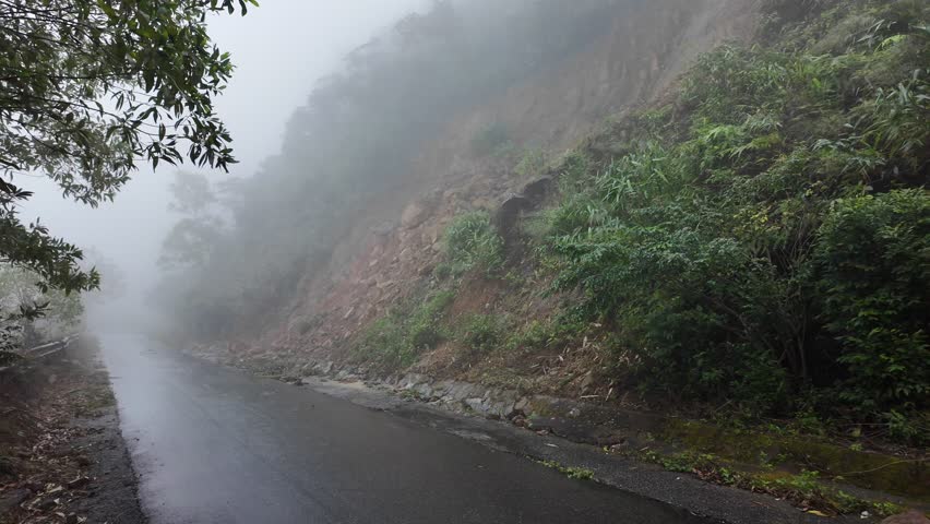 Foggy mountain road surrounded by lush greenery, perfect for concepts of adventure, travel, and nature holidays