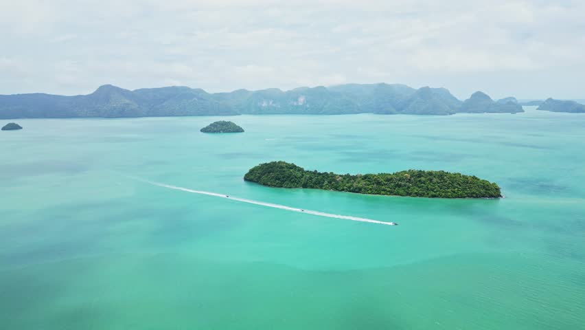 Aerial view of a beautiful tropical island with clear water, jetski, and boat in the serene sea, Kuah, Malaysia.