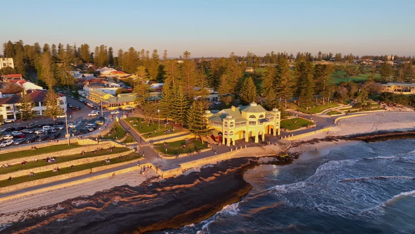 People enjoy sunset on Cottesloe Beach foreshore at sunset near famous building, Perth, Western Australia