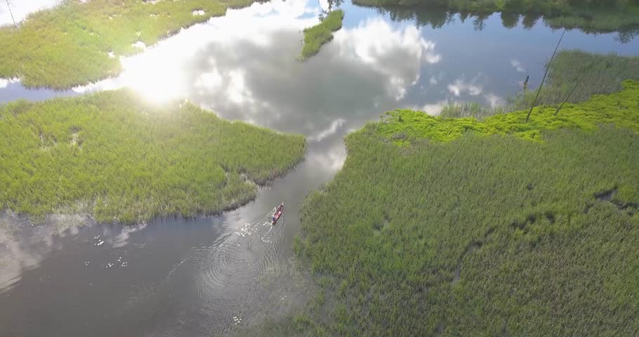 Two men row a canoe through shallow marshland in Lake Coeur d