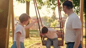 Child son, dad, mom play together on swing in park in summer, family walk. Son swinging on swing. Father, mom little boy swinging on swing in city park. Happy family. Parents kid boy, family weekend - Powered by Shutterstock - Get 15% off with code: PIKWIZARD15