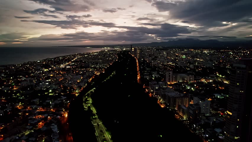 Rising Panoramic Aerial View over Santo Domingo Cityscape and Mirador Sur Park, Twilight
