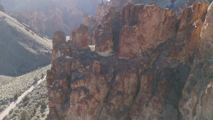 Drone fast fly over rock formations at Leslie Gulch Oregon to reveal canyon and windy dirt road