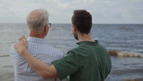 Adult son and elderly father walking together along bayshore, enjoying talking and spending time. Adult man supports for senior people. Intergenerational relationships and care for older people. - Powered by Shutterstock - Get 15% off with code: PIKWIZARD15