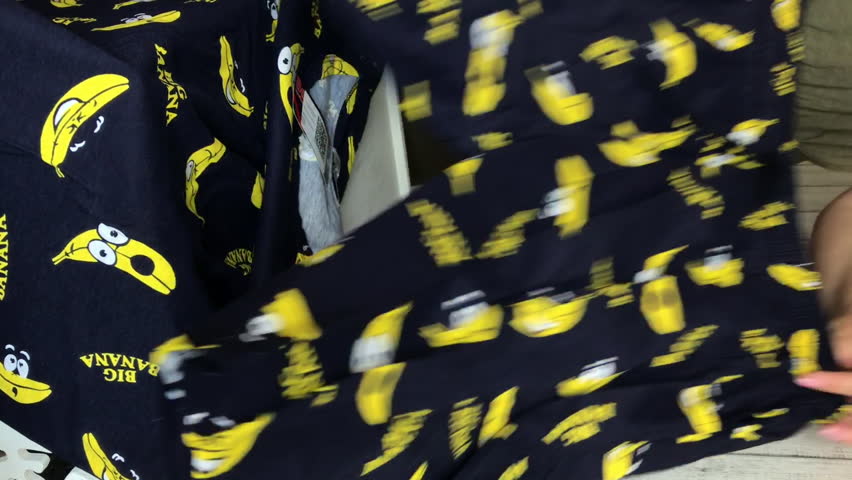 A woman is doing a product review on a marketplace. Men pajamas, shorts, and t-shirt. Close up. Vertical video.
