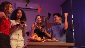 Asian friends, including a middle-aged man and a young woman, enjoy an office party with RGB lights, fried chicken, grilled food, hamburgers, grape wine, and champagne, celebrating together at night. - Powered by Shutterstock - Get 15% off with code: PIKWIZARD15