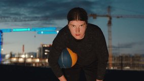 Portrait of female basketball girl at night holding a ball standing in front of illuminated construction in evening. Young sportswoman doing sport at night, training, making efforts  - Powered by Shutterstock - Get 15% off with code: PIKWIZARD15