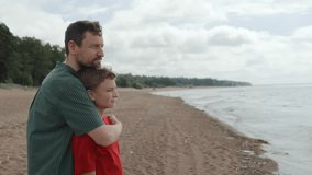 Father and teenage son take leisure walking along coastline of bay. Talking and sharing stories and jokes, smiling and enjoying togetherness. They stop to look at skyline. Family bonding - Powered by Shutterstock - Get 15% off with code: PIKWIZARD15