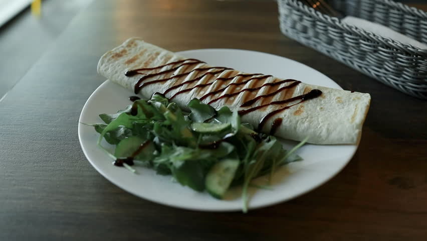 Tortilla wraps with chicken and fresh vegetables on white plate in cafe. Close up view. High quality photo