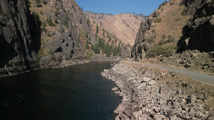 Aerial above Salmon River and road in Riggins Idaho with mountains on sunny day