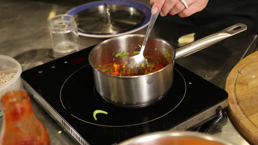 Pouring water, Jug cooking, Water tomato. Person pouring water from jug into pan vegetable tomato sauce on induction stovetop.