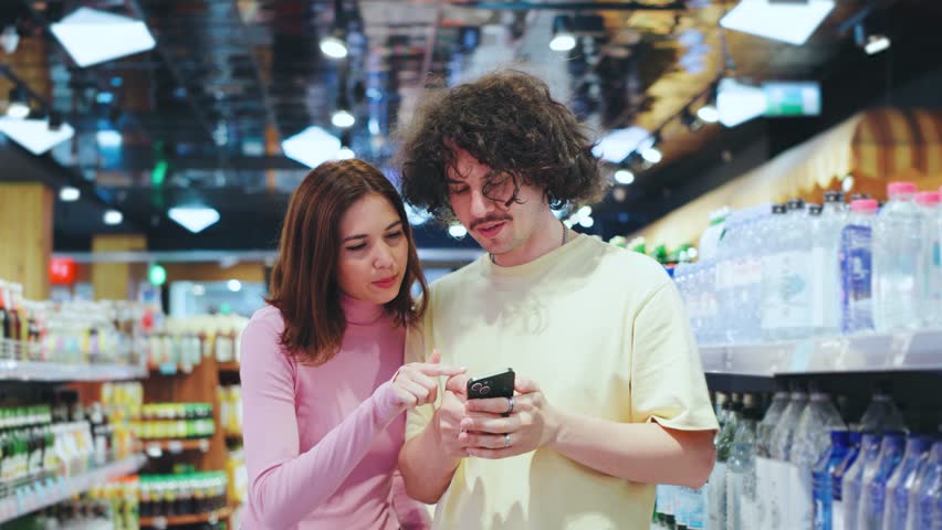 A couple happily engaged in a delightful shopping experience within a vibrant and modern grocery store, exploring colorful aisles filled with various fresh food items and products - Powered by Shutterstock - Get 15% off with code: PIKWIZARD15