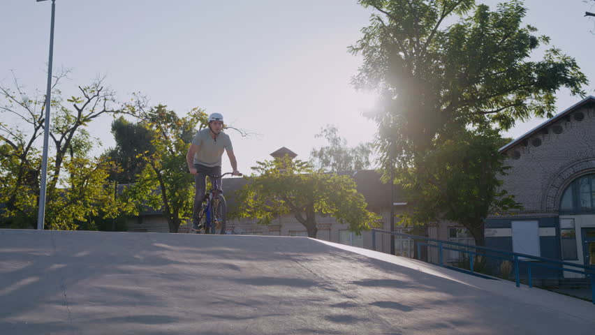 Hardworking sportsman in protective headwear performing turn of front wheel while floating in air. Extreme activity lover jumping on bicycle for overcoming internal fears at freestyle competition.