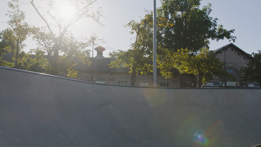 Fearless man in white helmet picking up speed while rising above skatepark slide and making flip in air. Adventurous person feeling adrenaline while making flying trick with sports bicycle.