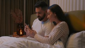 Caucasian couple man woman husband wife boyfriend girlfriend together watching movie mobile phone smartphone gadget online internet browse networking glued stuck addict bed bedroom home interested web - Powered by Shutterstock - Get 15% off with code: PIKWIZARD15