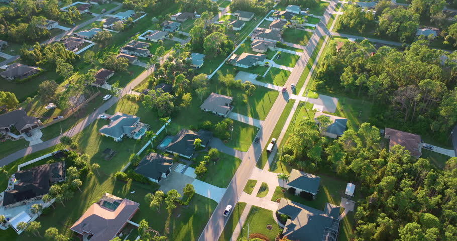 Cars driving on suburban street in Florida small town. American rural landscape with private houses in North Port quiet residential area.