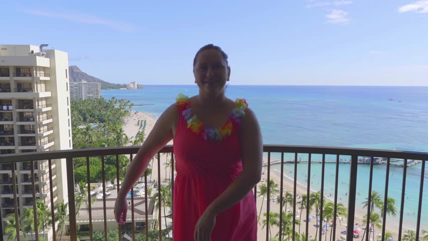 Woman dances the hula dance, in the background a beautiful view of Waikiki Beach in Honolulu, Hawaii from above in 4k slow motion 60fps