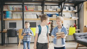 Three elementary school boys, each carrying backpacks and books, walk together down the school corridor on their way to the next class, chatting and laughing - Powered by Shutterstock - Get 15% off with code: PIKWIZARD15