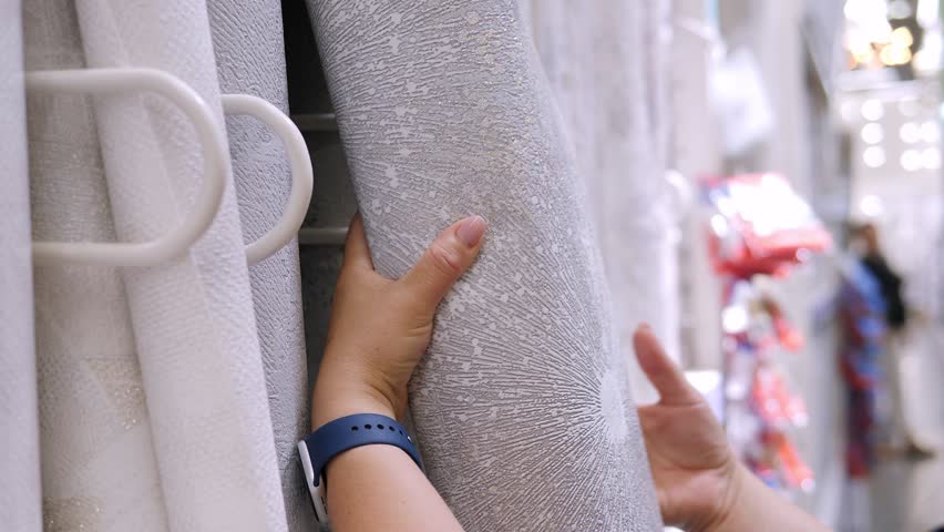 Close-up of a woman choosing wallpaper in a building supplies store. Preparation for repair. 