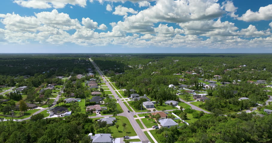 Small town rural street traffic with driving cars in North Port, Florida. American suburban landscape with private homes in quiet residential area.
