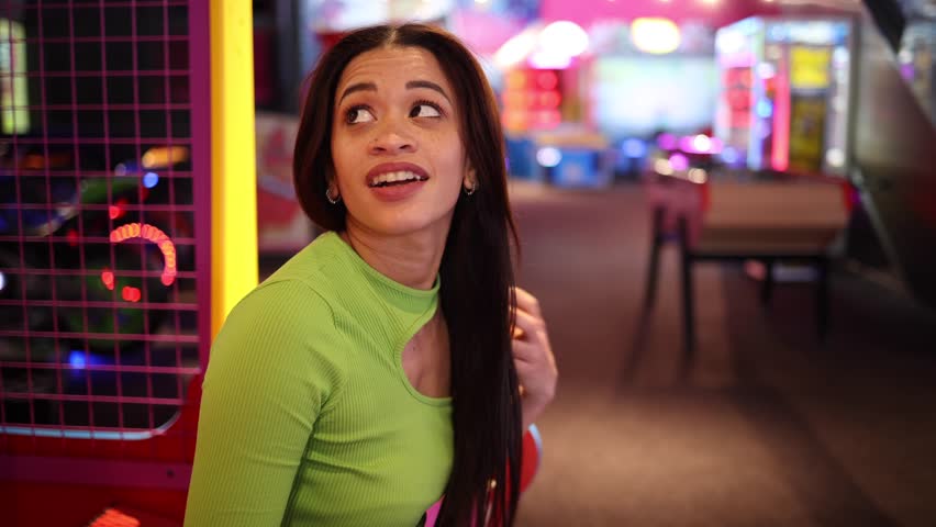 young woman with a bright smile posing at an arcade, with colorful lights in the background. Smiling Woman Enjoying Time at the Arcade