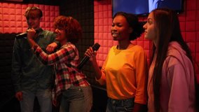 group of friends enjoying karaoke, singing and smiling in a cozy, colorful room. Friends Singing Karaoke and Having Fun Together - Powered by Shutterstock - Get 15% off with code: PIKWIZARD15