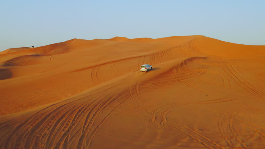 White SUV Climbing A Giant Dune In The Desert In Dubai, United Arab Emirates, Middle East