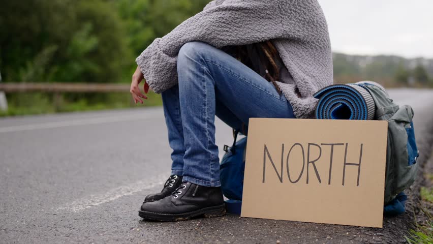 Unrecognisable person waiting for a car ride beside the road.