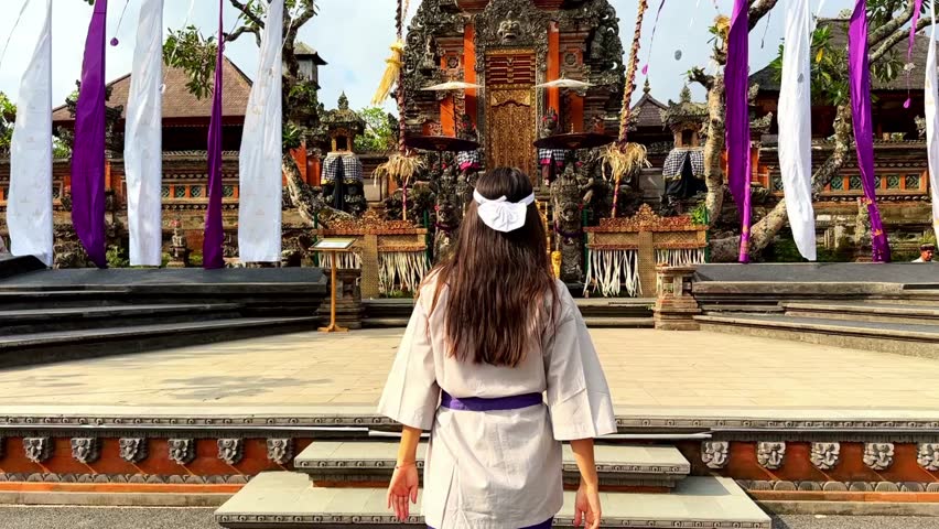 A beautiful woman visits Pura Taman Saraswati Temple in Ubud. Asian landscape, ancient red Hindu temple