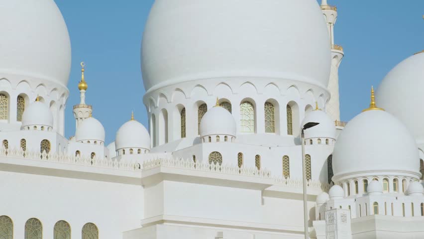 Domes of Sheikh Zayed Grand Mosque in Abu Dhabi, UAE, one of the largest mosques in the world against blue sky. White marble domes of Islamic art and architecture. Popular Arabic landmark