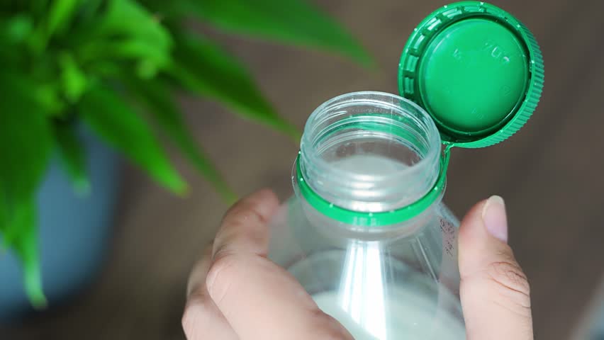 Stationary plastic cap on a PET bottle. The new design means the cap remains attached to the bottle after opening, making the entire package easier to collect and recycle. High quality 4k footage