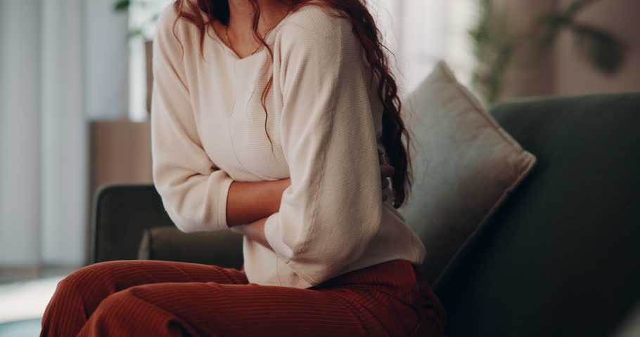 Woman, stomach and pain with discomfort or cramps in food poisoning, indigestion and bloating in home. Female person, tummy ache and gut health with abdominal muscle strain, menstrual cycle or nausea