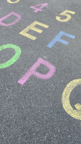 alphabet and numbers are drawn with color paint on a children's asphalt playground to learn and play. the alphabet educational element learning space. Vertical video