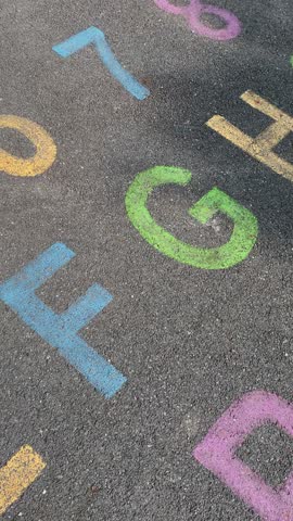 alphabet and numbers are drawn with color paint on a children's asphalt playground to learn and play. the alphabet educational element learning space.