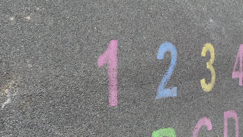 alphabet and numbers are drawn with color paint on a children's asphalt playground to learn and play. the alphabet educational element learning space.