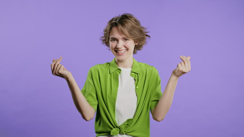 Young woman with money gesture on violet studio background. Rich lady smiling