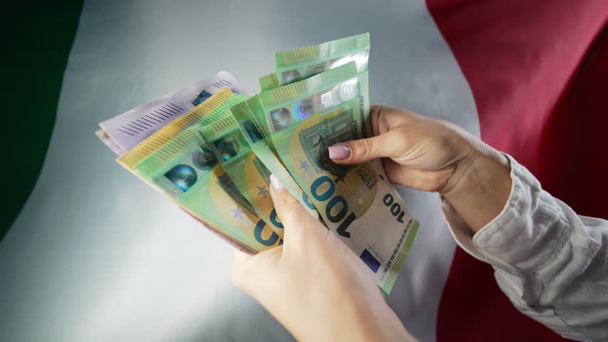 Counting money euros EUR on waving italian national flag background. Finance, economic crisis, Italy EU currency, symbol of independence.
