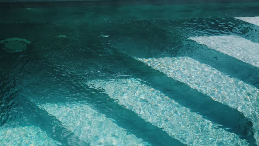Steps in the pool with blue ceramic tile mosaic. Relax in the backyard of a country house

