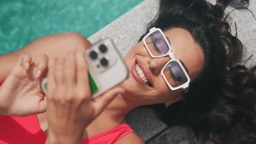 Beautiful girl in pink swimsuit lying on the edge of the pool with smartphone in hand. Tourist using mobile phone in the pool. Relax in luxury pool
 - Powered by Shutterstock - Get 15% off with code: PIKWIZARD15