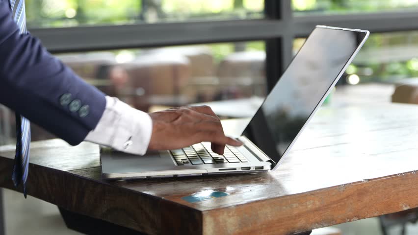 A Businessman in a Rush Using His Laptop at a Cafe, Multitasking During a Busy Day, A professional man working on his laptop in a cafe, typing quickly while managing multiple tasks - Powered by Shutterstock - Get 15% off with code: PIKWIZARD15