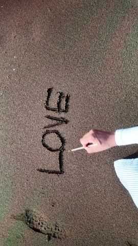 Hand writing love you in the sand on the beach	