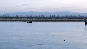 Children sledding on a frozen lake at dusk with mountains in the distance - Powered by Shutterstock - Get 15% off with code: PIKWIZARD15