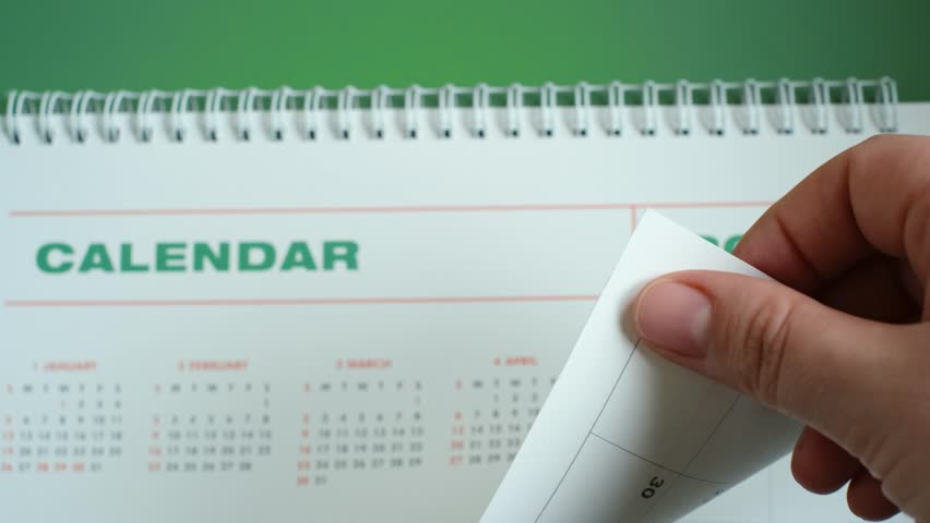 White calendar 2025 on green background close-up, planning concept.