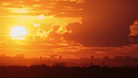 Sunset over cityscape with cranes and buildings on the horizon, time lapse. City skyline photography for poster, wallpaper, banner, header - Powered by Shutterstock - Get 15% off with code: PIKWIZARD15