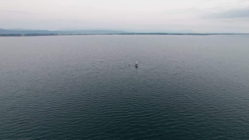 Drone travels around Japanese fishing boat in Lake Biwako, islands background, Asian travel destination under foggy skyline