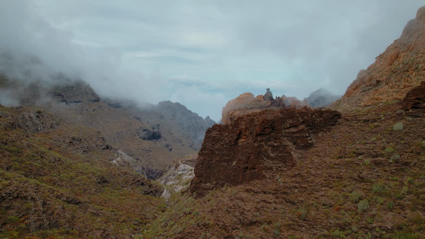 A foggy mountainous landscape with rugged cliffs. Video shows a blurred, chaotic view of nature, captured during a drone crash, with grass and debris.
