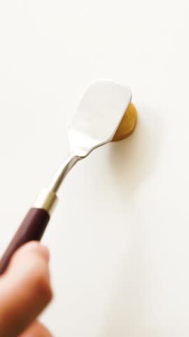 palette knife smears gold bronzer on white background, bright sun rays