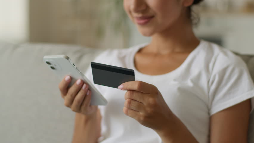 Close up unrecognizable happy smiling Indian woman Arabian lady girl female using mobile phone at home buying purchase online shopping credit bank card buy store shop internet app order food delivery